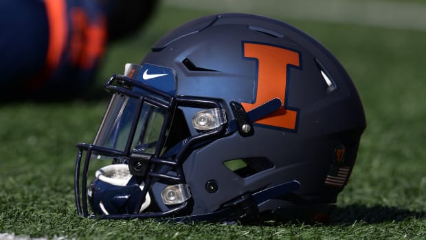 Illinois Fighting Illini helmet sits on the field as players stretch before the start of the game between the Illinois Fighting Illini and the Michigan Wolverines at Memorial Stadium.